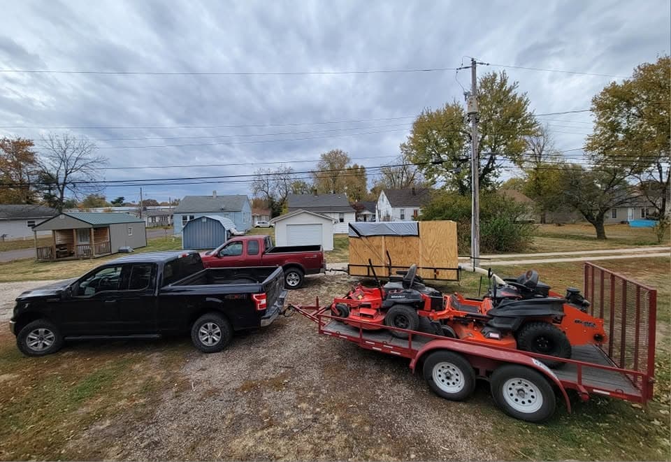 Trucks and trailer loaded with riding mowers ready for a job
